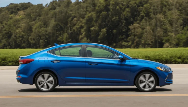A blue compact sedan driving down an open road with greenery and trees in the background.